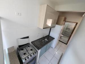 eine kleine Küche mit Herd und Spüle in der Unterkunft Residêncial Maria de Castro in Mairiporã