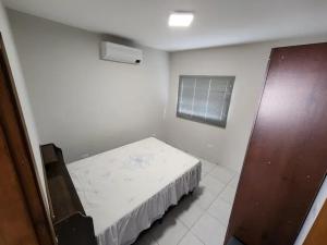 ein kleines weißes Zimmer mit einem Bett und einem Fenster in der Unterkunft Residêncial Maria de Castro in Mairiporã