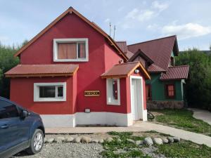 una casa rossa e verde con un'auto parcheggiata di fronte di La Protegida a El Chalten