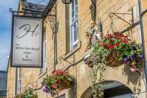 un edificio con cestas de flores a su lado en The White Hart Royal, Moreton-in-Marsh, Cotswolds en Moreton in Marsh