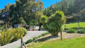 a garden with palm trees and a house at Tiny Home Container house Above the Vines in Waikakaho
