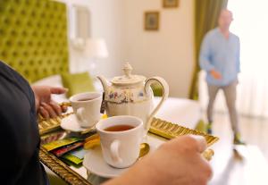 a person holding a tea pot and cups on a table at B&B Palazzo Cerami in Catania