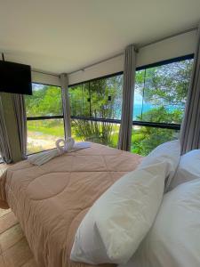 a bedroom with a large bed with a large window at Raizes do Mar Hotel - Pé Na Areia - Opções de Suites com Ofuro Aquecido, SPA Privativo, Vista ao Mar ou Montanha, com Estacionamento e Café Incluso in Guarujá
