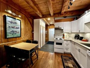 kuchnia z białymi szafkami i stołem oraz jadalnia w obiekcie Waterfront Timber Frame Cottage! w mieście Ucluelet