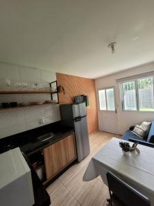 una cocina con mesa y una cocina con refrigerador en Estrela do Mar Studio, en Itapema