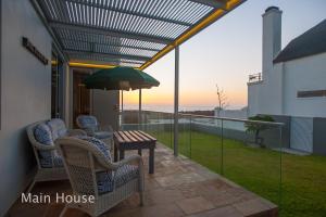 a patio with chairs and a table and an umbrella at Bokkombaai in Bloubergstrand