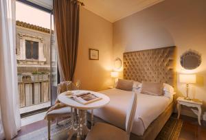 a bedroom with a bed and a table and a window at B&B Palazzo Cerami in Catania