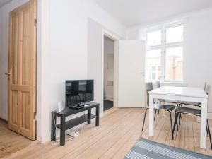 a white living room with a table and a television at Holiday home in Denmark in Ringkøbing