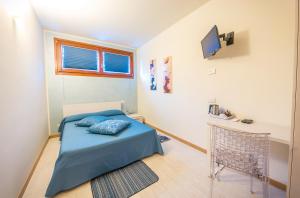 a small bedroom with a blue bed and a tv at Agriturismo Ca' La Pergola in Verona
