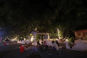 un grupo de personas sentadas bajo un árbol por la noche en MARUTI RESORT & VILLA's, en Sasan Gir 230 fotos más