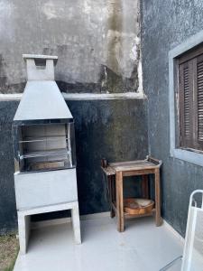 a stove and a stool next to a building at Casa perto do mar in Capão da Canoa