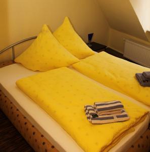 Una cama con sábanas amarillas y una toalla. en Weinstube Schwarzamsel, en Speyer