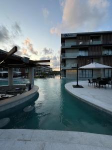 a building with a pool of water in front of a building at Porto Alto Resort - Porto de Galinhas in Porto De Galinhas