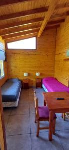 a room with two beds and a table in a cabin at Depto Castillo in El Bolsón