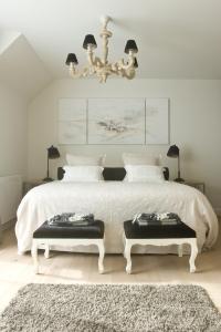 a bedroom with a large white bed with two benches at B&B Interludium in Nijlen