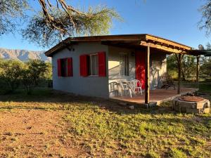 a small house with a deck with a table and chairs at El Ashva casa de campo y santuario de caballos in Las Calles