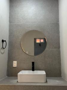 a bathroom sink with a round mirror on a wall at La Gran Manzana in Tizimín