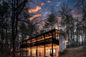 a glass house in the woods at night at Cozy Cabin With Hot Tub, Grill, Fire Pit & Game Room in Blue Ridge