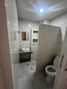 a white bathroom with a toilet and a sink at TKH The Bed in Ban Khlong Bang Krathiam