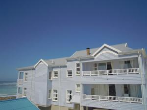 a white house on the beach with the ocean behind it at Point Village Accommodation - Alista in Mossel Bay
