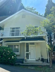 南小国町Whole house rental 天然温泉付きコテージRAI駐車場付き黒川温泉街まで車で5分的白色的房子,设有白色的门和阳台