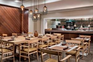 a restaurant with wooden tables and chairs and a kitchen at Sheraton Suites Market Center Dallas in Dallas