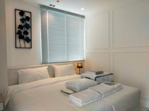 a white bed in a bedroom with a window at The Empire Tower Pattaya 614 in Jomtien Beach