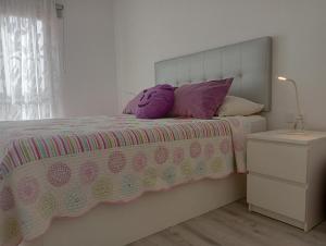 a bedroom with a bed with purple pillows on it at CASA SORAYA El Medano in El Médano