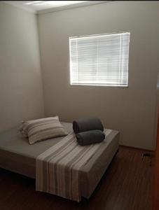 a bed with two pillows on it in a room with a window at ap 22 amaryllis in Poços de Caldas