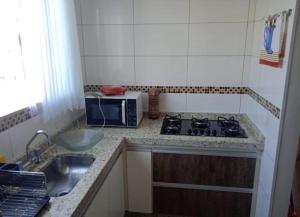 a kitchen with a stove and a sink and a microwave at ap 22 amaryllis in Poços de Caldas