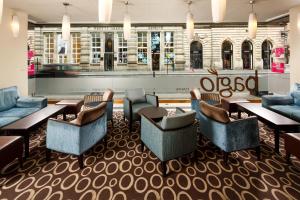 a lobby with couches and tables in a restaurant at Mercure Glasgow City Hotel in Glasgow