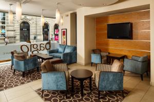 a lobby with furniture and a flat screen tv at Mercure Glasgow City Hotel in Glasgow