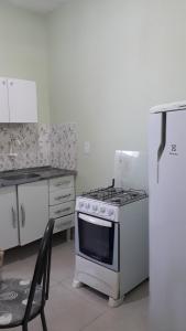 Una cocina con una estufa y una silla dentro. en Porto apartamento 1, en Porto Seguro