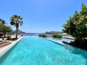 a pool at the beach with palm trees and the ocean at Luxury Beachfront Stay - 5 Pools! in Careyes +23 photos