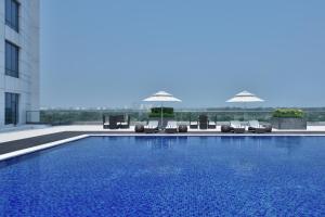 a swimming pool with chairs and umbrellas on a building at The Westin Kolkata Rajarhat in Kolkata