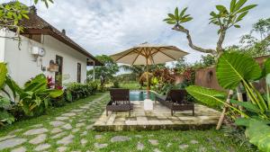 a patio with an umbrella and chairs and a pool at Tenggala Villa Ubud by Mahaputra in Ubud