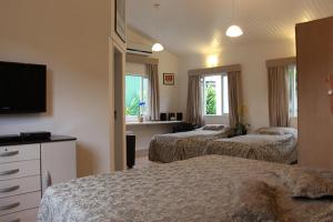 a hotel room with two beds and a flat screen tv at Paraty Bungalows Bar E Hotel in Paraty