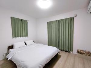a bedroom with a white bed and green curtains at Newly built two-story house! 2 minutes to the station, parking lot, easy access to Disneyland, close to restaurants and shops! in Chiba