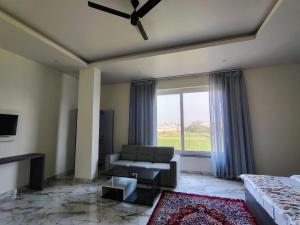 a living room with a couch and a large window at Tarachand Resort in Soh Sarāi