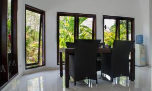 a dining room with a table and chairs and windows at Villa Danison in Umeanyar