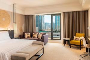 a bedroom with a bed and a couch and a window at Le Royal Meridien Beach Resort & Spa Dubai in Dubai