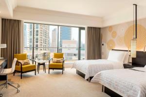 a hotel room with two beds and a desk and chairs at Le Royal Meridien Beach Resort & Spa Dubai in Dubai