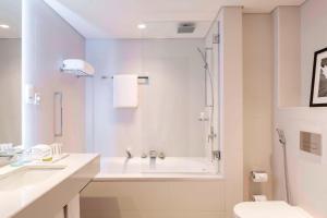 a white bathroom with a tub and a sink at Le Royal Meridien Beach Resort & Spa Dubai in Dubai