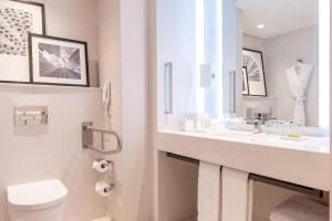 a white bathroom with a sink and a toilet at Le Royal Meridien Beach Resort & Spa Dubai in Dubai