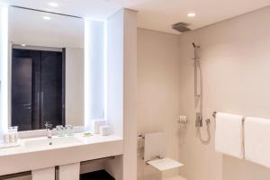 a white bathroom with a sink and a shower at Le Royal Meridien Beach Resort & Spa Dubai in Dubai