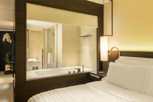 a bedroom with a tub and a bed and a mirror at Le Royal Meridien Beach Resort & Spa Dubai in Dubai
