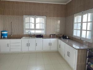 a kitchen with white cabinets and a sink and two windows at Dar Slimane in Monastir