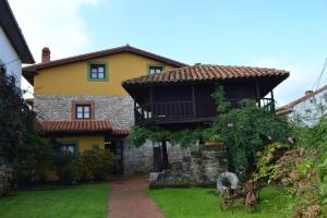 a yellow house with a balcony in the yard at La Fonte in Naves