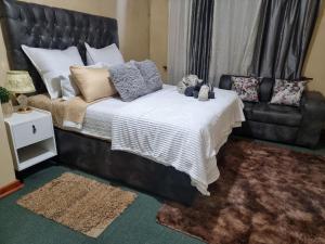 Un dormitorio con una cama grande y un sofá. en The Leafy Haven- A feel of home!, en Harare