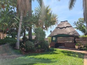 Un pequeño edificio con techo de paja con palmeras. en The Leafy Haven- A feel of home!, en Harare